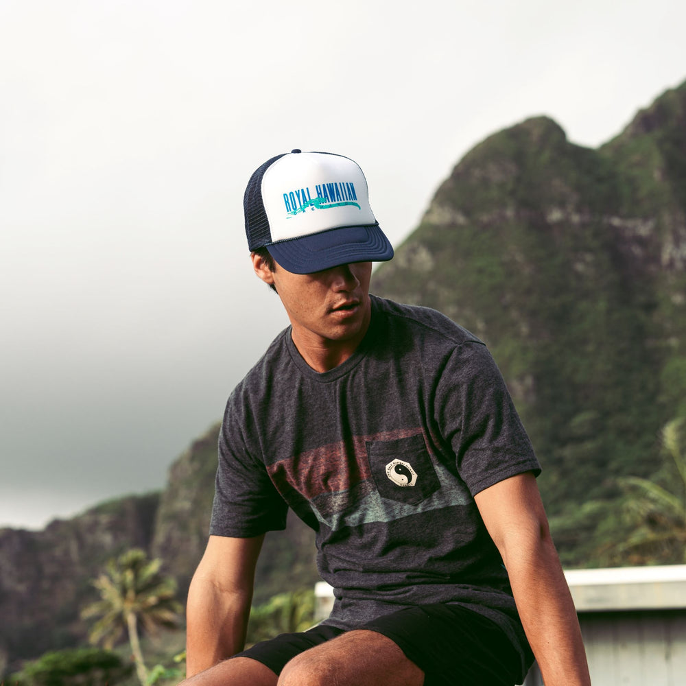 man wearing navy and white trucker hat with Royal Hawaiian Orchards and wave design