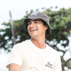 close up of man wearing gray bucket hat with royal hawaiian orchards logo